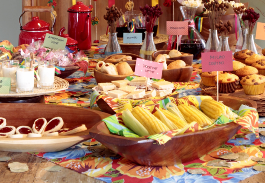 Mesa com comidas típicas de festa junina, como quentão e amendoim doce, que são produtos sazonais.